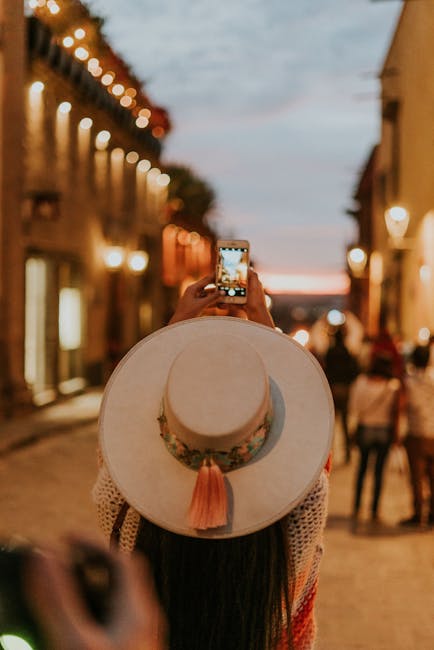 Donna con cappello che fotografa una via illuminata, analogia con aggettivi di prima classe che descrivono qualità.
