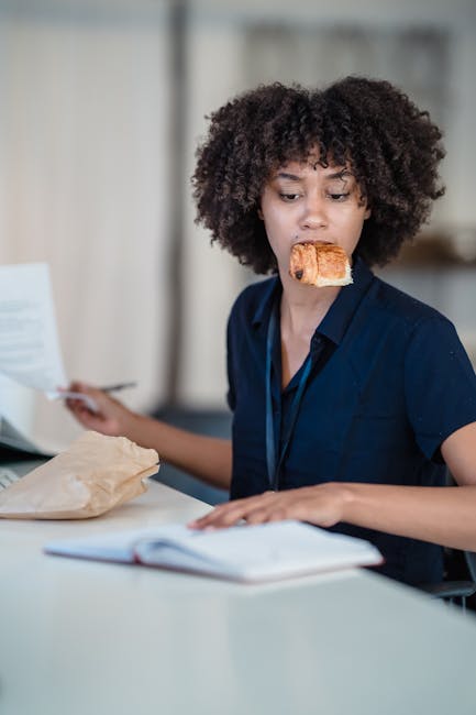 Donna lavora con orari flessibili mangiando brioche, gestione del tempo e pausa pranzo efficiente, lavoro agile e produttività.