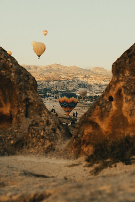 Mongolfiere colorate che volano sopra il paesaggio roccioso della Cappadocia, creando un'atmosfera magica e suggestiva.