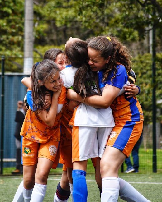 Ragazze calciatrici esultano abbracciandosi dopo la vittoria, metafora della competizione e delle aspettative disattese nel concorso dirigenti scolastici