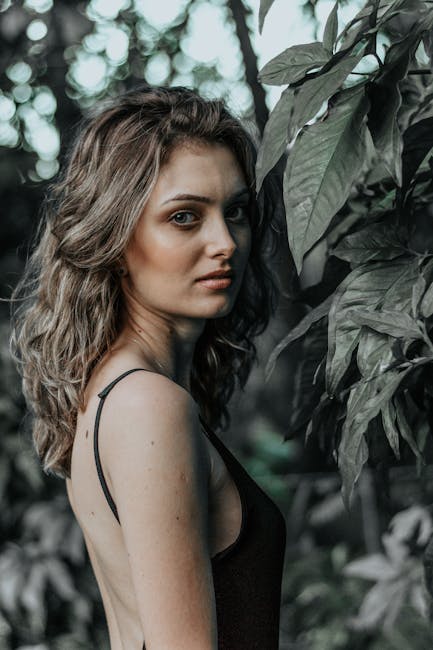 Donna e natura: un'immagine per Amante di Gramigna Ritratto di donna misteriosa tra le foglie, evocativo dell'atmosfera di Amante di Gramigna, sguardo intenso e profondo