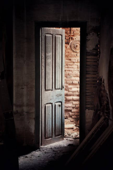 Porta socchiusa in edificio abbandonato con muro di mattoni, simbolo di accesso a zone proibite e misteriose