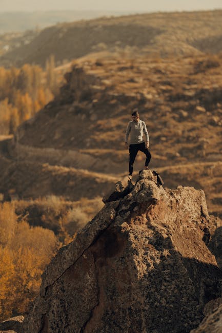 Uomo in cima a roccia in paesaggio arido che ricorda la superficie di un pianeta alieno, esplorazione spaziale