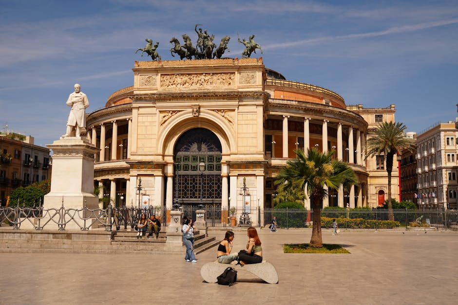 Teatro Massimo di Palermo, sfondo per Classici in Strada, con persone sedute e statua di Vincenzo Bellini in primo piano.
