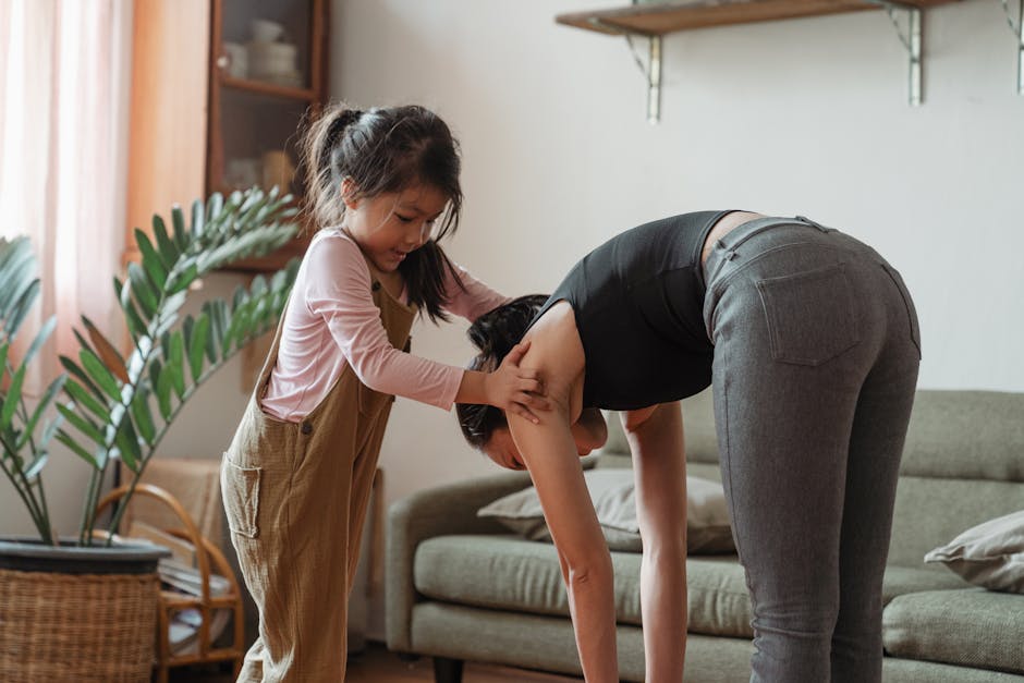 Bambina supporta la madre durante esercizi di stretching domestici, un esempio di resilienza familiare e supporto reciproco