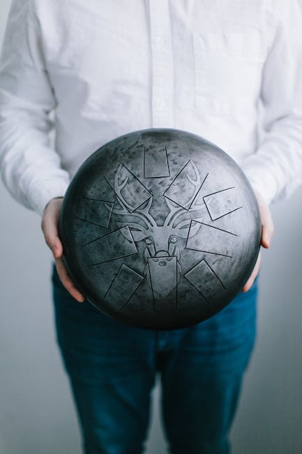 Hang drum con incisione di cervo, strumento musicale per musicoterapia e riscoperta di sé, tenuto in mano da persona.