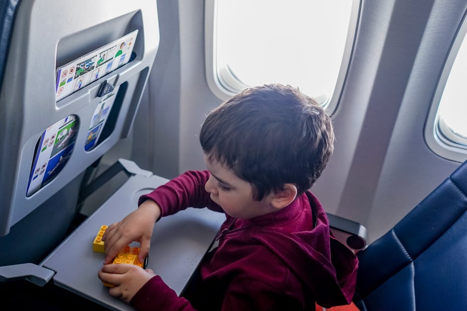 Gioco creativo in viaggio: apprendimento per bambini Bambino gioca con costruzioni colorate in aereo, stimolando creatività e apprendimento durante il viaggio, ideale per articolo su strumenti musicali creativi.
