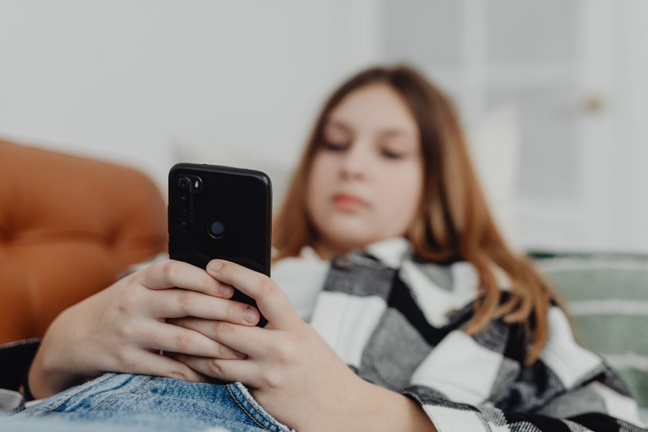 Adolescente con smartphone in mano, simbolo del divario generazionale sull'uso del digitale e del dibattito sugli schermi