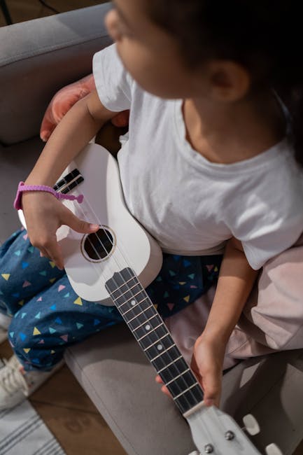 Bambina che suona l'ukulele bianco, strumento musicale per l'apprendimento e lo sviluppo cognitivo dei bambini