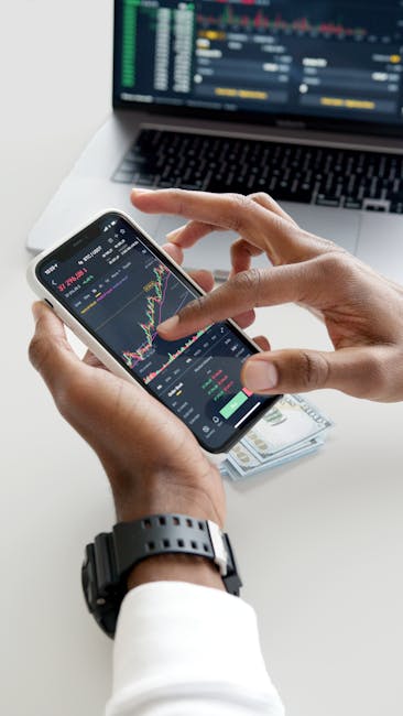 Analisi di grafici finanziari su smartphone con laptop sullo sfondo, concetto di investimento e finanza personale