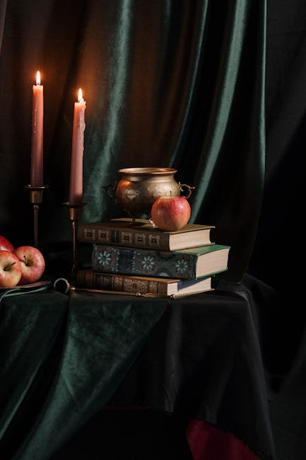 Natura morta con candele accese, libri antichi, calderone e mele rosse, evocativa dell'atmosfera epica e letteraria dell'Eneide.