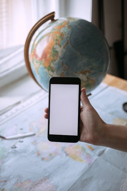 E-learning globale: istruzione online e connessione mondiale E-learning e globalizzazione: mano con smartphone su mappa e mappamondo, simbolo dell'istruzione online e connessa al mondo.