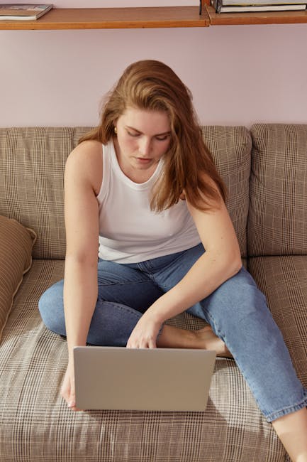 Donna che lavora al computer seduta sul divano, visualizzando angoli adiacenti sullo schermo per studio o lavoro.