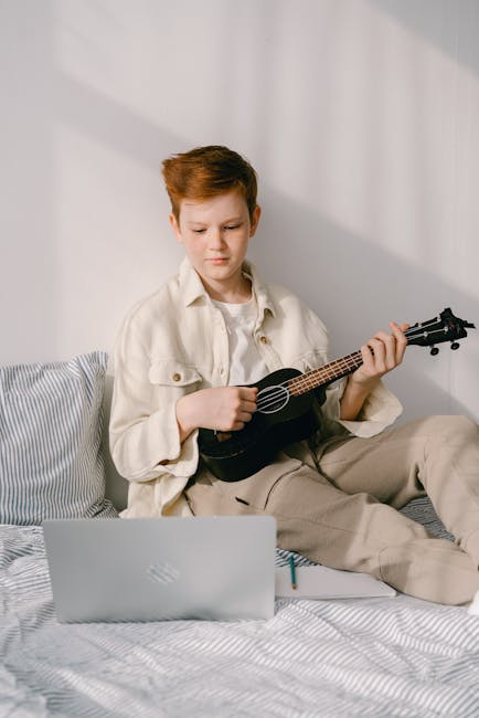 Studente lombardo suona ukulele davanti al laptop, esempio di apprendimento digitale e sviluppo del talento giovanile in Lombardia