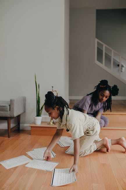 Due bambine afroamericane giocano con spartiti musicali sul pavimento in legno, attività musicale per bambini