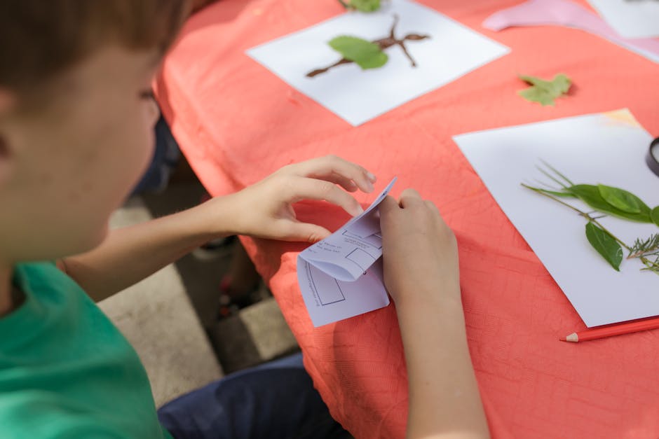 Bambino piega un foglio durante attività didattica Stem Up Your Future a Milano con stazioni meteorologiche scolastiche.