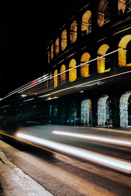 Colosseo illuminato di notte con scie luminose di autobus: vantaggi abbonamento mezzi pubblici Roma, trasporto efficiente e sostenibile