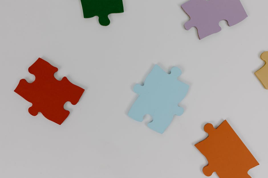 Puzzle colorati sparsi su sfondo bianco, metafora di connessione e sviluppo cognitivo legato a musica e apprendimento.