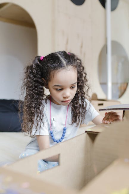 Bambina concentrata che gioca con scatole di cartone, un'attività creativa per lo sviluppo ritmico e l'apprendimento.