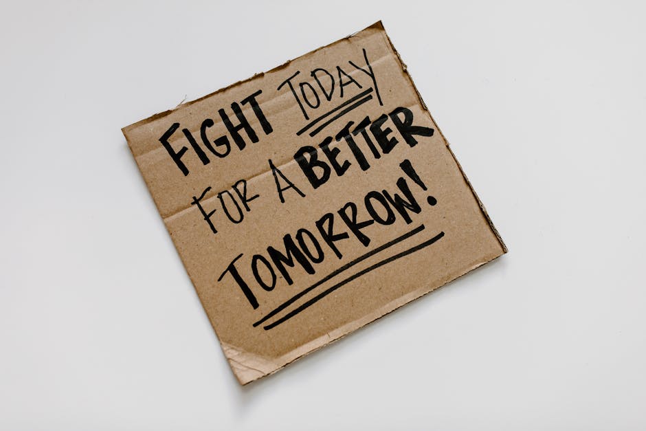 Cartello di cartone con la scritta 'Fight Today for a Better Tomorrow', simbolo di resilienza e cambiamento come Camilla.