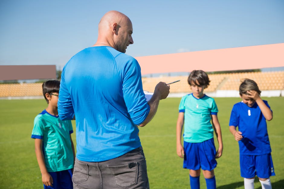 Allenatore di calcio spiega tattiche a giovani calciatori durante le Giornate FAI per le Scuole, promuovendo la cittadinanza attiva e la tutela del patrimonio.