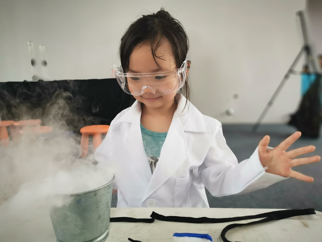 Bambina con camice da scienziato e occhiali protettivi che osserva un esperimento con fumo denso uscire da un secchio metallico, simbolo di curiosità scientifica e apprendimento