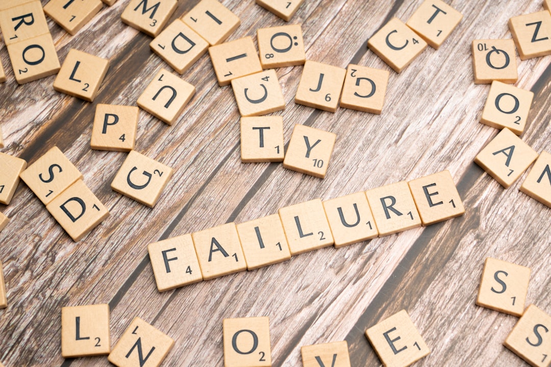 Parole FAILURE scritte con tessere di Scrabble su sfondo legno, metafora del fallimento scolastico e della severità eccessiva